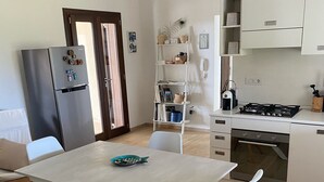 A modern kitchen with a dining table, chairs, a refrigerator, and a stove.