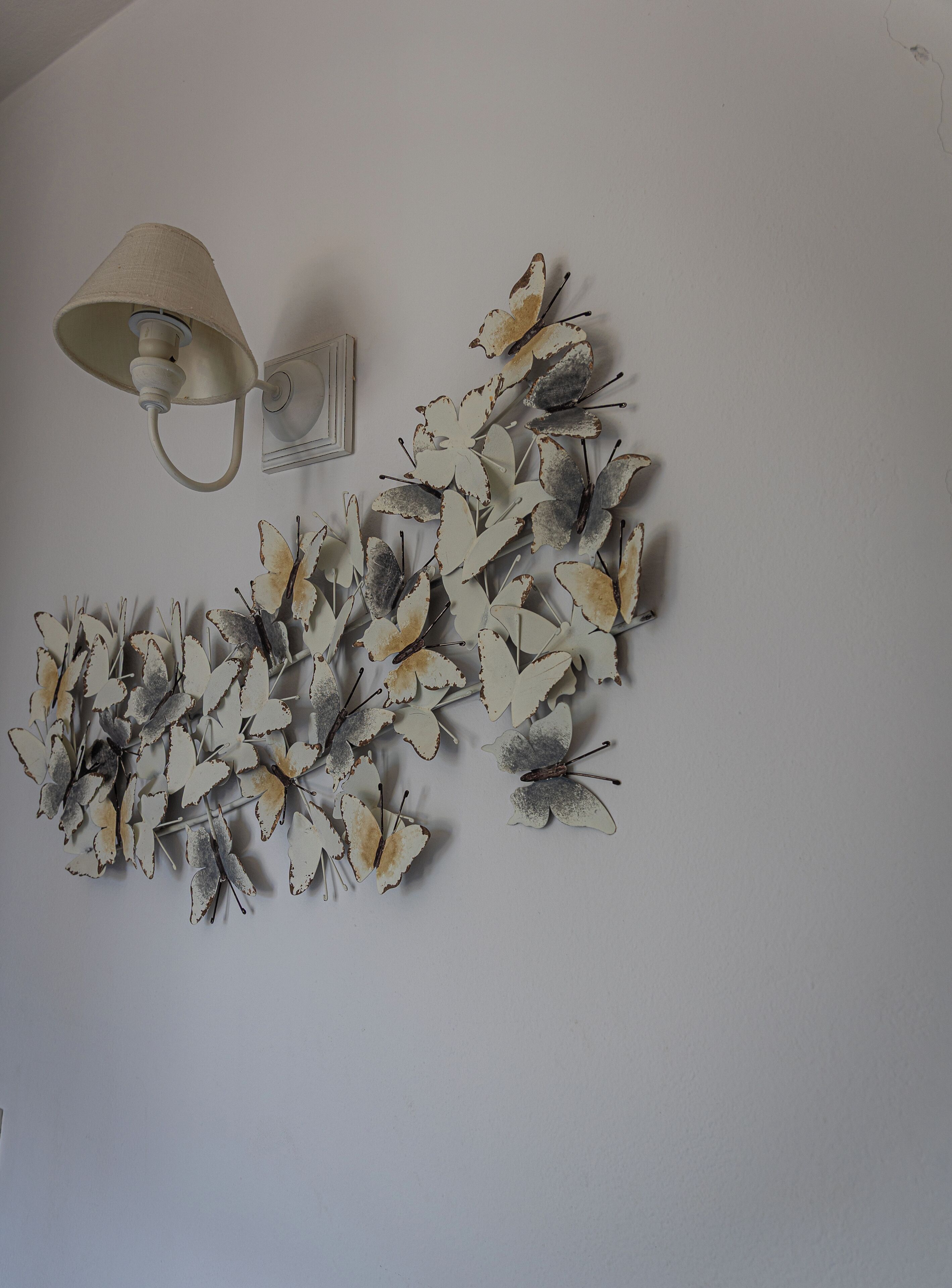 A wall with a decorative butterfly arrangement and a wall-mounted lamp.
