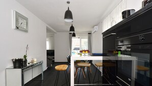 Eine moderne Küche mit einem schwarzen Backofen, einer weißen Arbeitsplatte und Holz-Barhocker.