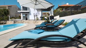Ein Poolbereich mit Liegestühlen und einem großen Sonnenschirm.