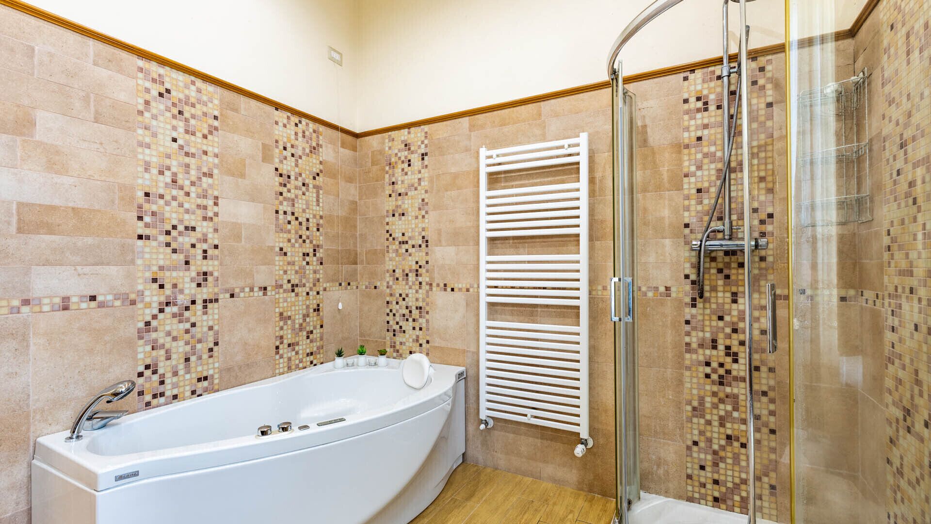 A bathroom with a freestanding bathtub, a glass-enclosed shower, and mosaic tile walls.