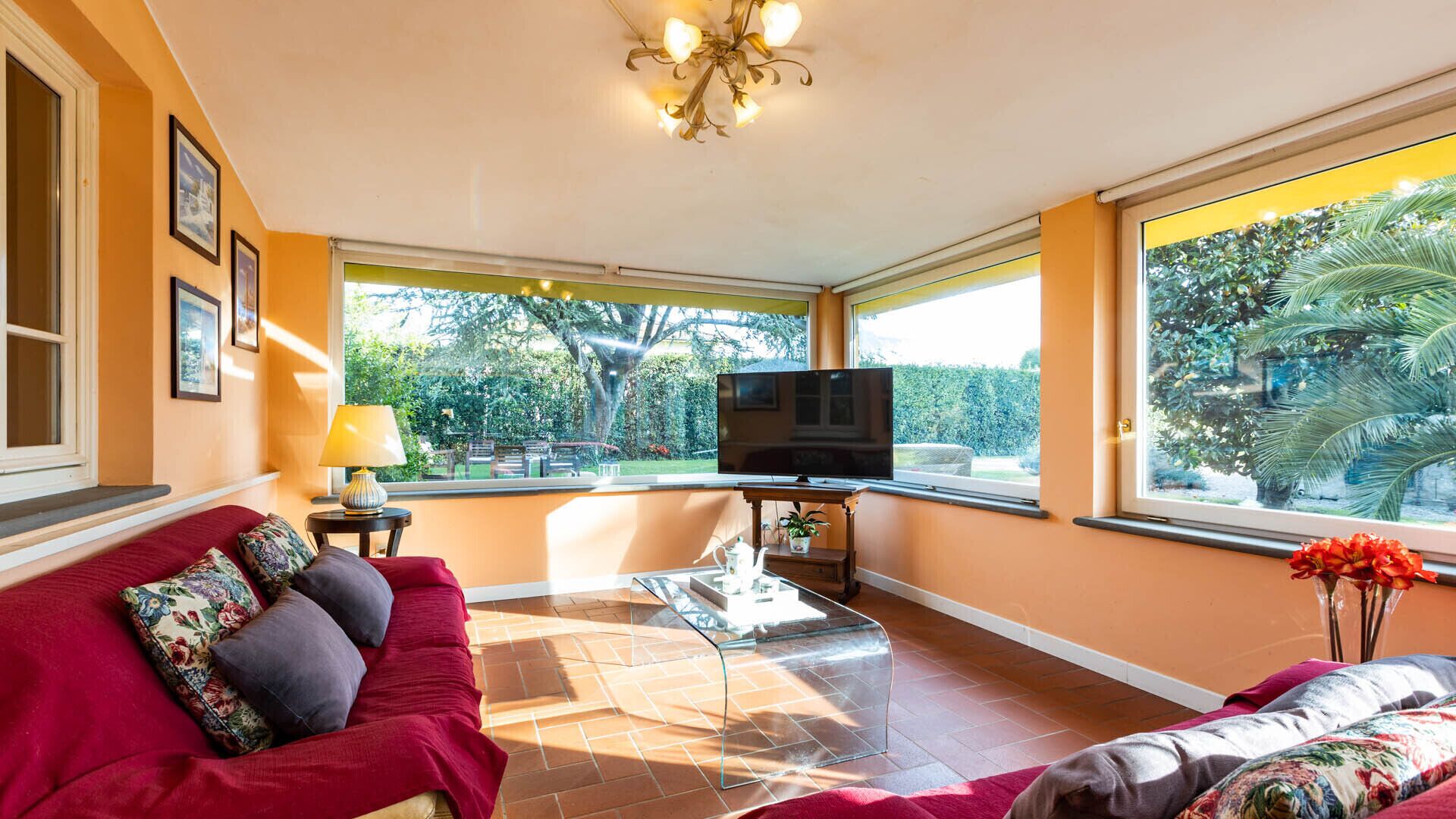 A living room with a TV, sofa, and large windows.