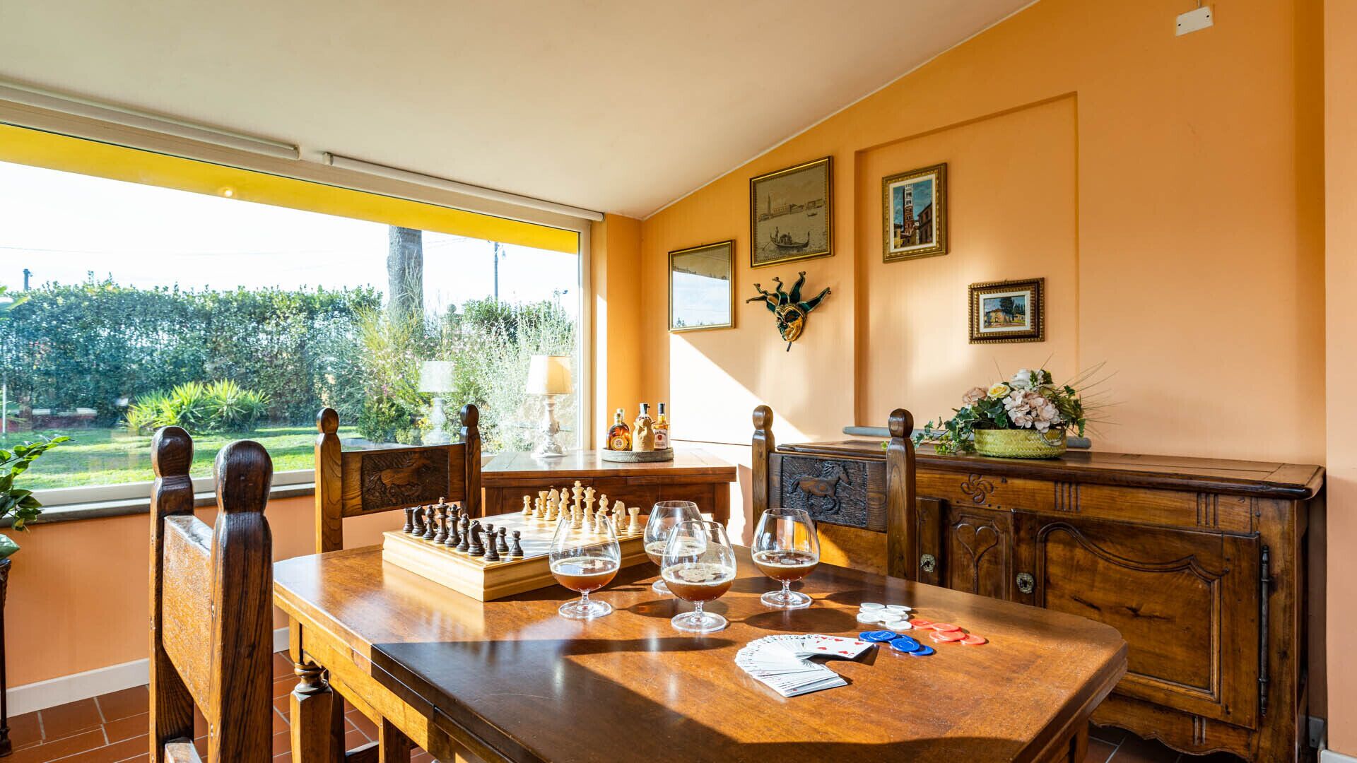 Un coin repas avec une table en bois dressée pour le dîner, un jeu d’échecs et des verres à vin.