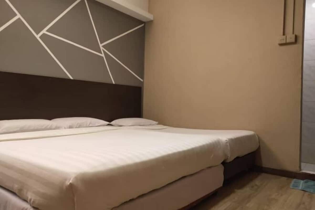 A hotel room with a bed, a geometric wall design, and a wooden floor.
