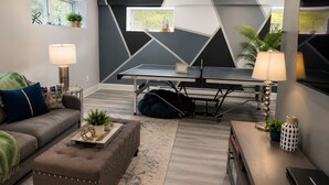 A modern living room with a ping pong table, a sofa, a coffee table, and a TV. - Luxury Vacation home in the Poconos close to the lake and community pool.  (Albrightsville)