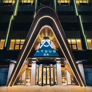 A hotel entrance with a prominent sign, a revolving door, and a modern building facade. - Atour Hotel (Chaozhou)