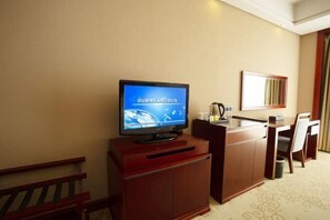 A hotel room with a television on a wooden cabinet, a desk with a chair, and a mirror on the wall. - Runying Hotel (Tianchang)