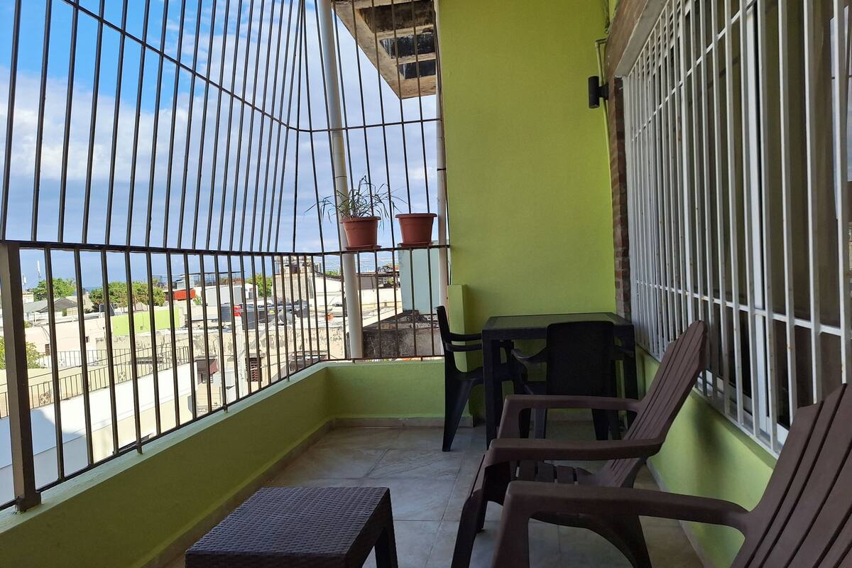Ein Balkon mit Tisch und Stühlen, einem Blumentopf und Blick auf die Straße.