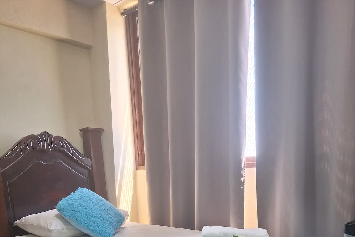 Ein Bett mit Kopfteil, Kissen, einer blauen Decke und einem gefalteten Handtuch.