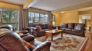 A spacious living room with leather sofas, a wooden coffee table, and a large patterned rug. - Heart of Killington location. Pet-friendly! (Killington)