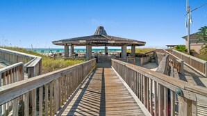 A wooden boardwalk leading to a beach pavilion with a sign reading "Welcome to Kitty Beach."
