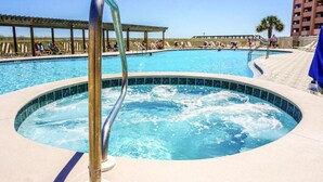 A swimming pool with a hot tub, lounge chairs, and a covered area.