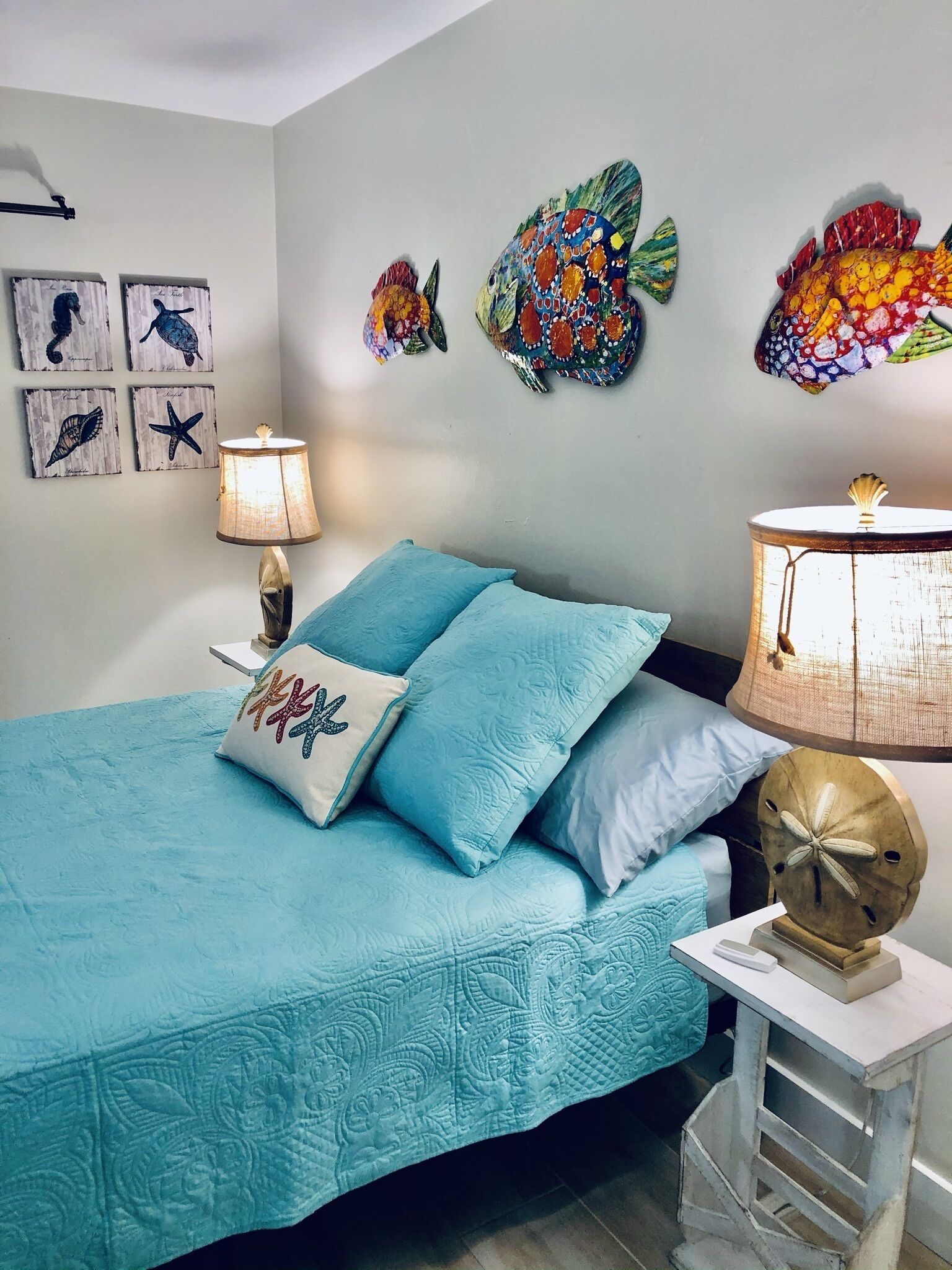 Un dormitorio con cama, almohadas, una lámpara y decoración en la pared.
