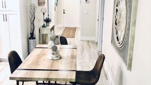 A dining area with a wooden table, four chairs, and a woven rug. - Newly Furnished! Minutes from beach, heated private pool, Elegant and Coastal!   (Naples)