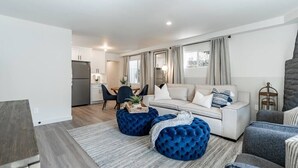 Ein modernes Wohnzimmer mit einer Couch, Hockern und einem Essbereich mit Stühlen und einem Tisch.