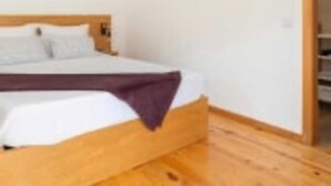 A single bed with a wooden headboard in a room with white walls and wooden flooring. - Douroparadise (Caldas de Moledo)
