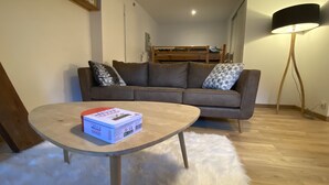 Una sala de estar con un sofá marrón, una mesa de centro redonda de madera y un alfombra blanco y mullido.