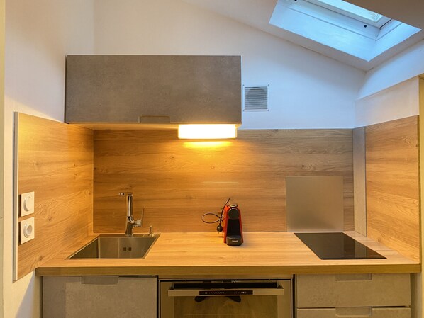 Una cocina compacta con tragaluz, pileta de acero inoxidable y lavavajillas integrado.