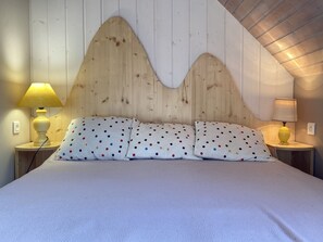 A bed with polka dot pillows, a wooden headboard, and two bedside lamps. - Joli chalet 60m2 proche du centre. parking. balcon (Cauterets)