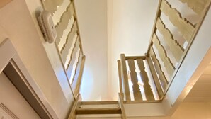 A wooden ladder leading to a door with a decorative ceiling pattern.