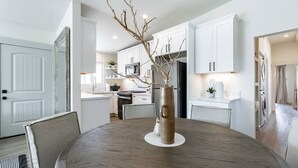 A modern kitchen with white cabinetry, a central island, and a dining table with chairs. - The Rosemont II - 2BR La Jolla Gem Near the Beach (San Diego)