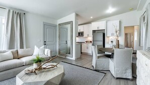 A modern living room with a sofa, coffee table, and a dining area with chairs. - The Rosemont II - 2BR La Jolla Gem Near the Beach (San Diego)