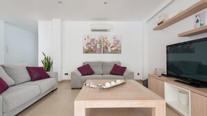 Ein modernes Wohnzimmer mit einem grauen Sofa, einem Holztisch und einem Flachbildfernseher auf einem Holzständer.