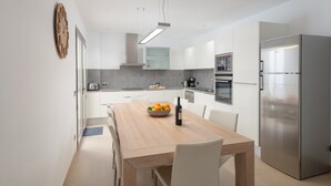 Eine moderne Küche mit Holztisch, Edelstahlgeräten und weißen Schränken.