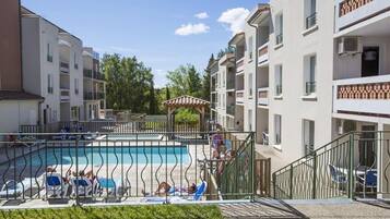 Relax by the pool surrounded by lounge chairs and umbrellas, with a gazebo nearby.