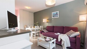 Un salon moderne avec un canapé rouge, une table basse blanche et un coin repas comprenant une table et des chaises blanches.