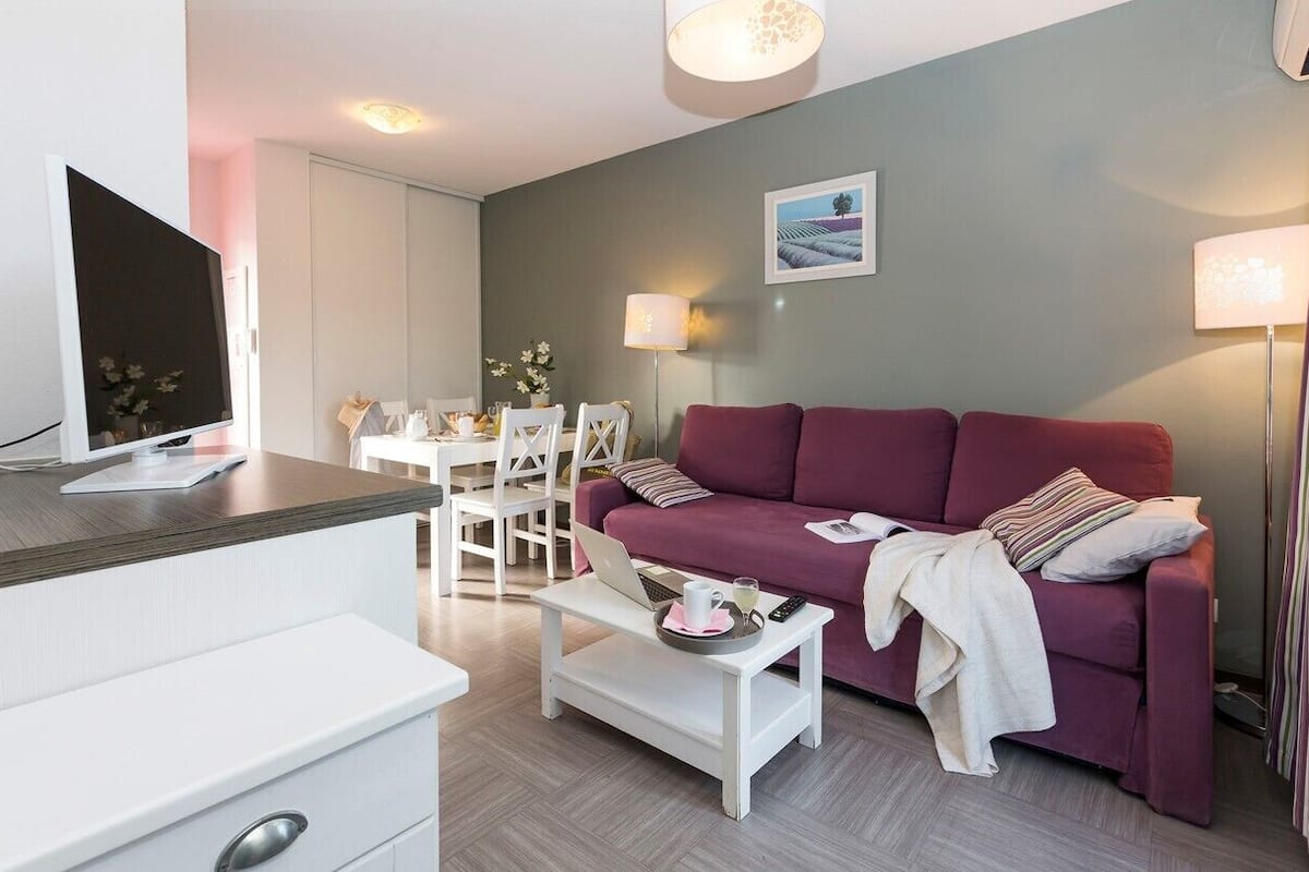 Un salon moderne avec un canapé rouge, une table basse blanche et un coin repas comprenant une table et des chaises blanches.