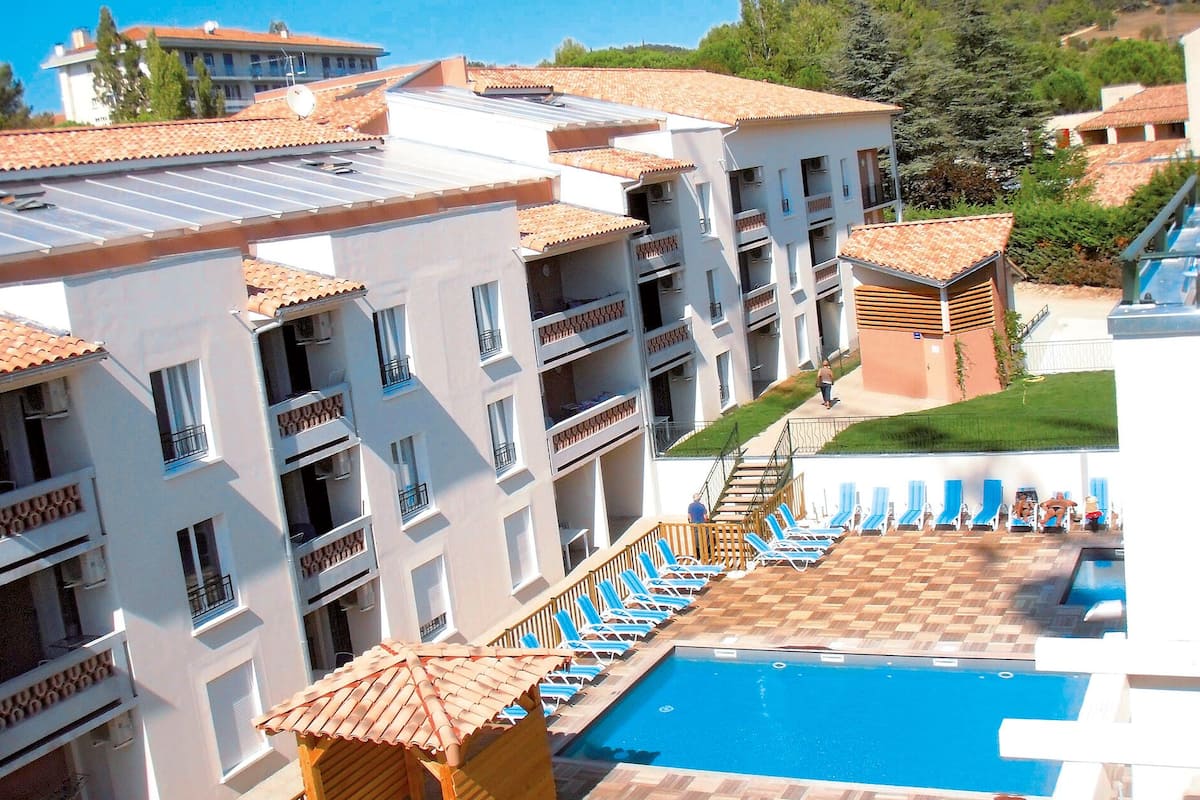 Un hôtel à plusieurs étages doté d’une piscine sur le toit, d’un espace extérieur aménagé et offrant une vue sur le paysage environnant.