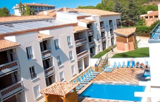 Un hotel de varios pisos con piscina en la azotea, mobiliario exterior y vistas del paisaje circundante.