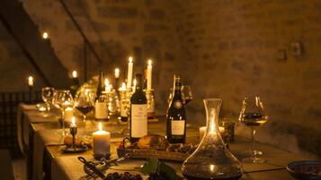 A long table set with wine bottles, glasses, candles, and food items, suggesting a dining or tasting event.
