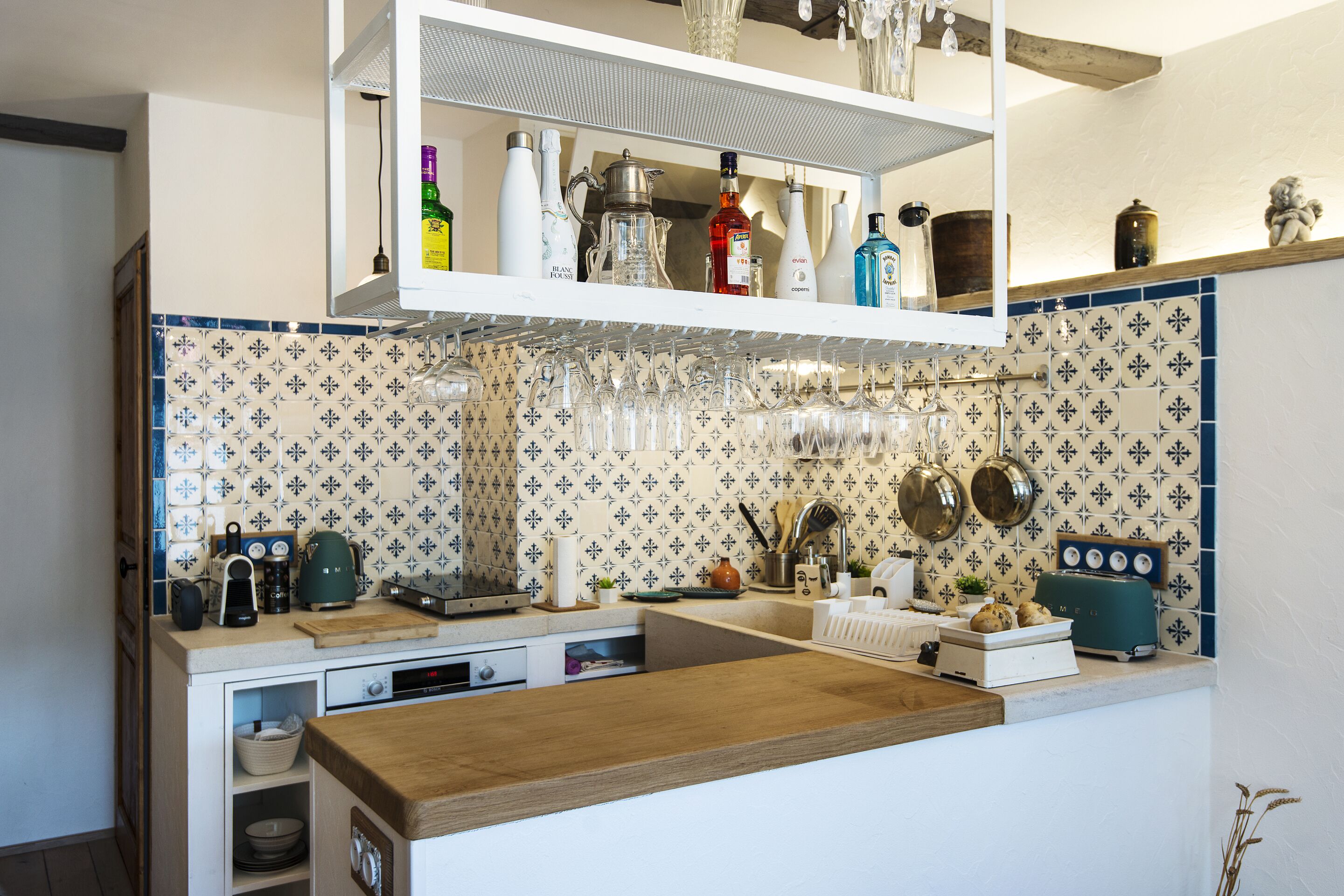 A kitchen with a wooden countertop, a built-in oven, a coffee machine, and a variety of kitchen utensils.