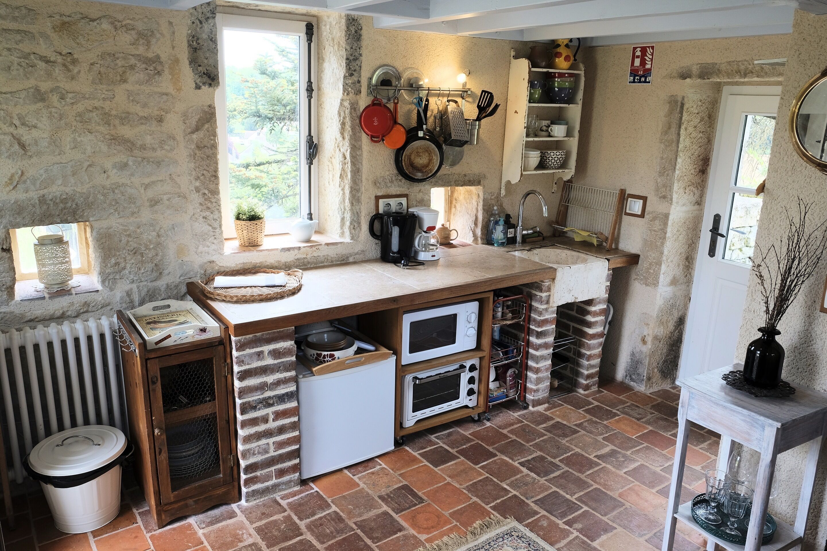 A rustic kitchen with stone walls, a wooden countertop, and a built-in oven.
