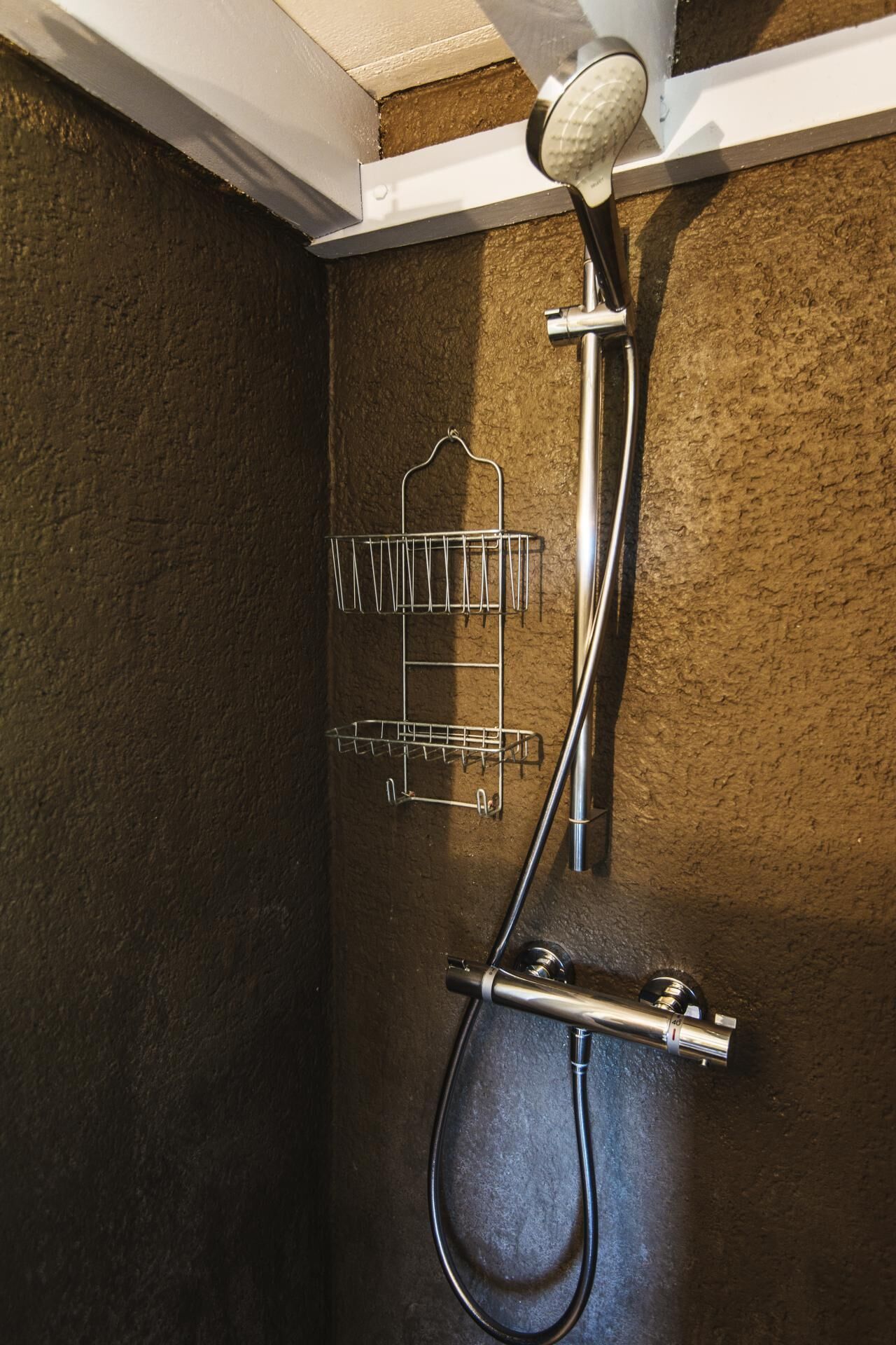 A shower with a metal rack and a handheld showerhead.