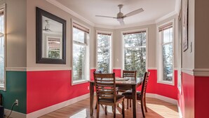 A dining area with a red and teal wall, wooden dining table, and chairs. - Large suite on the Knoll in a cul-de-sac w/ a private hot tub and pet friendly! (Silver Star Mountain)