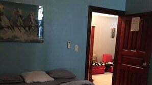 A bedroom with a bed, pillows, and a blanket. There is a painting on the wall and a door leading to another room. - Sunny and fun Costa Rica relax to enjoy (Coco)