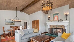 A living room with a fireplace, a dining area, and a chandelier. - Superb La Vida Riviera 2 BD 2BA Gorgeous Riviera Views, Walk Everywhere! (Santa Barbara)