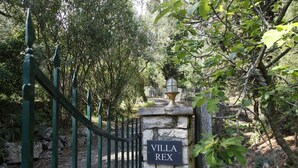 Un muro de piedra con un letrero que dice "Villa Rex" y una reja metálica.