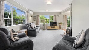 A spacious living room with a sofa set, a TV, and a fireplace. - Kapuka Paradise - Wharewaka Holiday Home (Wharewaka)