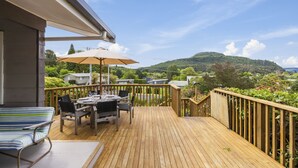 Une terrasse en bois avec une table et des chaises, un canapé à rayures et un parasol.