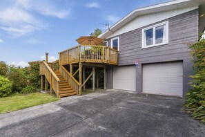 A two-story house with a wooden deck, a garage, and a well-maintained lawn.