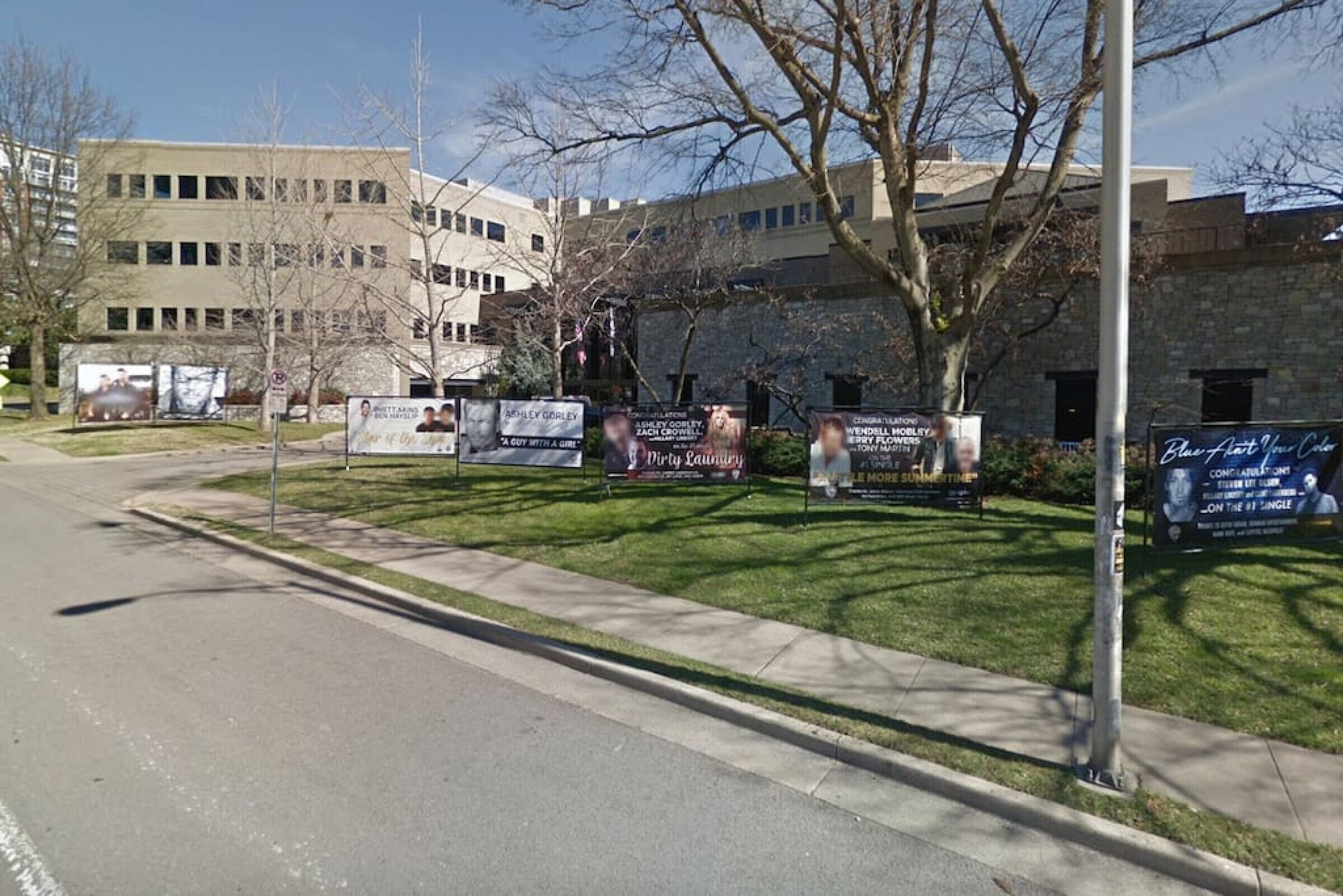 A building with multiple signs, a sidewalk, and a street.