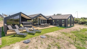 Ein modernes Haus mit überdachter Sitzgruppe, Essbereich und großem Fenster.