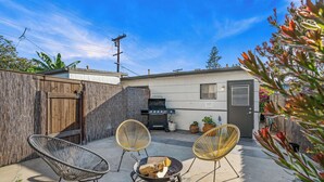 A backyard with a barbecue grill, two wicker chairs, and a fire pit. - SD Getaway - Boho Studio, Spacious Yard w/ BBQ (San Diego)