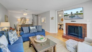A living room with a blue sofa set, a fireplace, and a television mounted above it. - Award-Winning Resort Amenities | Racquet Club 2 (Isle of Palms)