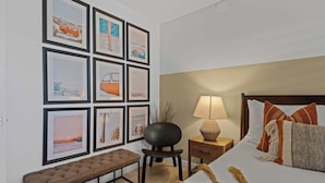 A bedroom with a bed, bedside table, lamp, and a bench.