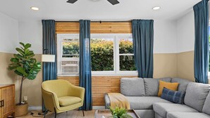 A modern living room with a sofa, armchair, and a large window with curtains.
